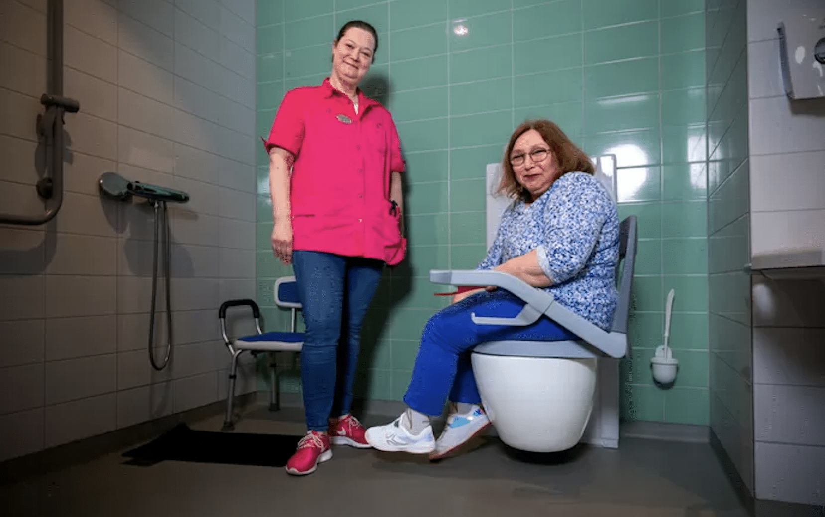 Benutzerin sitzt auf der drehbaren Toilette Bano neben der Leiterin des<br>Pflegeheims